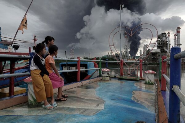 印尼中爪哇省奇拉卡帕市，印尼国家石油公司（Pertamina）的一个炼油厂的储油罐发生火灾，孩子们望着远处的黑烟。 - 俄罗斯卫星通讯社