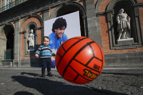 公民投票廣場的中央廣場，一個小男孩在馬拉多納的照片前玩足球。 - 俄羅斯衛星通訊社