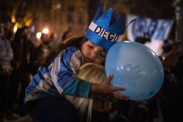 西班牙巴塞羅那，球迷們在為傳奇球星馬拉多納舉行慶祝活動時，一個孩子靠在母親的肩上。 - 俄羅斯衛星通訊社