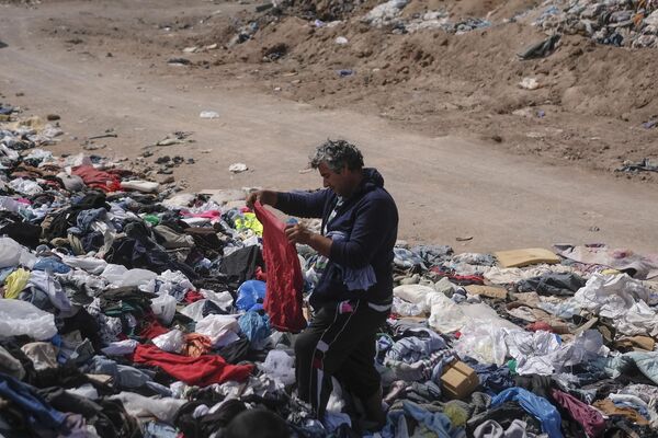 一名男子在废弃二手服装垃圾场中挑选衣物。 - 俄罗斯卫星通讯社