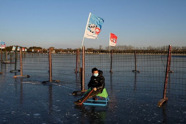 北京，一个男孩在结冰的湖面上滑冰，身边是2022北京冬奥会的宣传画。 - 俄罗斯卫星通讯社