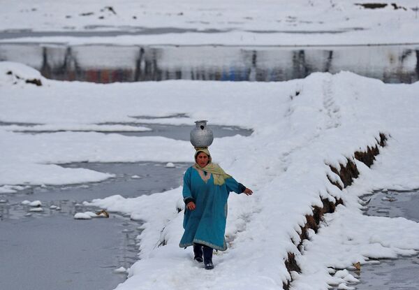 印度城市斯利那加市郊，一名女子头顶水罐走在被白雪覆盖的田野里。 - 俄罗斯卫星通讯社