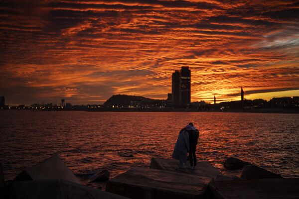 西班牙巴塞罗那，一对夫妇在防波堤上观看日落。 - 永利官网卫星通讯社
