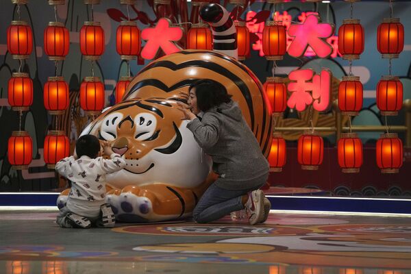 中國北京，一名女子帶著孩子在商場里的老虎雕塑前玩耍。 - 俄羅斯衛星通訊社
