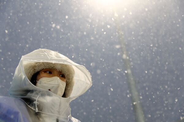 一名奧運組委會女工作人員站在大雪紛飛中的國家冬季兩項中心。 - 俄羅斯衛星通訊社