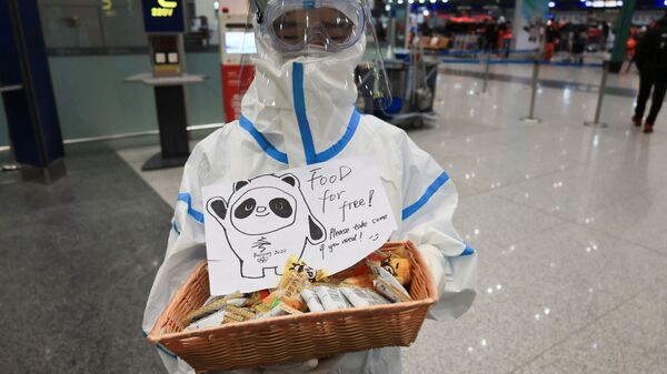 Работник в защитном костюме раздает бесплатную еду в Международном аэропорту Пекина  - 永利官网卫星通讯社