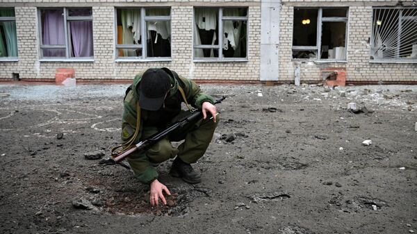 Сотрудник народной милиции ДНР возле воронки от снаряда у школы Горловки - 俄羅斯衛星通訊社
