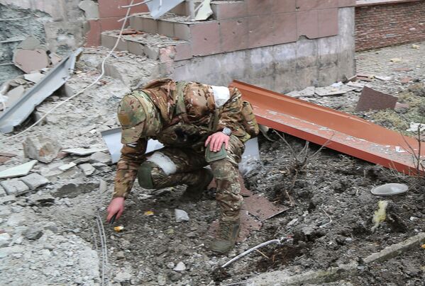 一名士兵在顿涅茨克一栋住宅楼前检查爆炸造成的弹坑，该住宅楼在炮击中被毁。 - 俄罗斯卫星通讯社