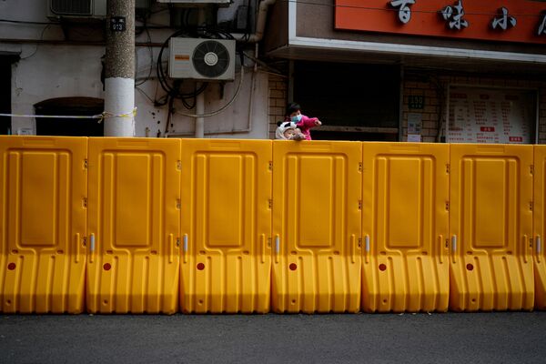 上海新冠疫情期间，一位家长带着两名儿童从黄色围挡内向外张望，2022年3月26日。 - 俄罗斯卫星通讯社