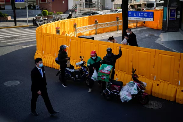 外賣小哥通過黃色圍擋向封控區域內的居民傳遞食物，2022年3月23日。 - 俄羅斯衛星通訊社