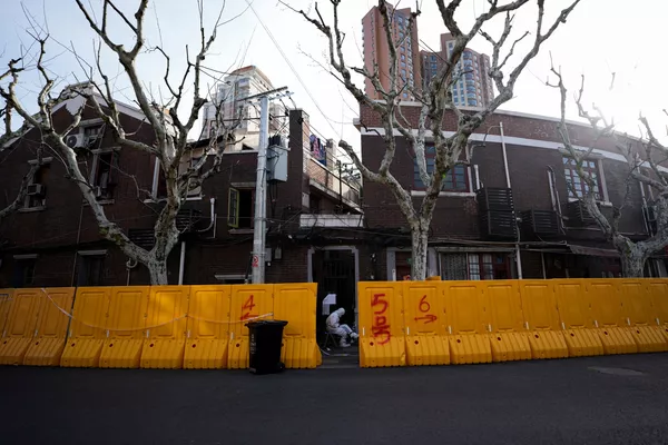 上海新冠疫情期間，一名身穿防護服的保安坐在黃色圍擋中間的一個社區入口處，2022年3月24日。 - 俄羅斯衛星通訊社
