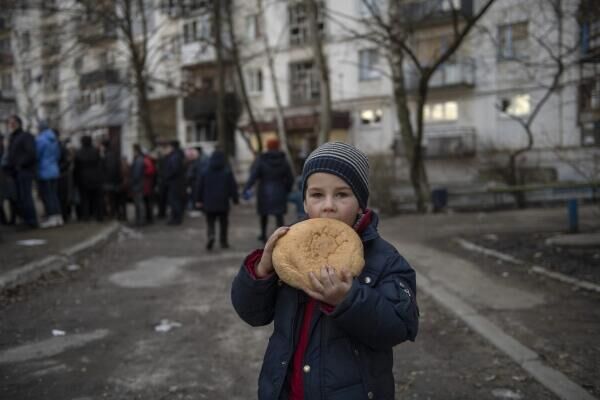 “夜狼”摩托车俱乐部成员在乌克兰鲁比日内市向民众分发人道主义援助物资，一名儿童拿着面包，2022年3月29日。 - 俄罗斯卫星通讯社