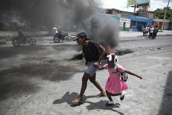 海地首都太子港的一名妇女领着孩子途径反对暴力的示威游行，2022年3月29日。 - 俄罗斯卫星通讯社