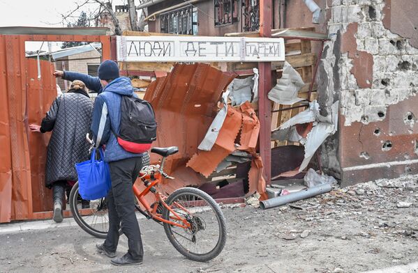 馬里烏波爾居民來到一處住房前，門上掛著牌子，寫著“人們·兒童·老人”。 - 俄羅斯衛星通訊社