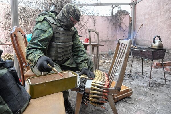 頓涅茨克人民共和國人民警察的一名士兵在馬里烏波爾一棟房子的院子里裝機槍彈帶。 - 俄羅斯衛星通訊社