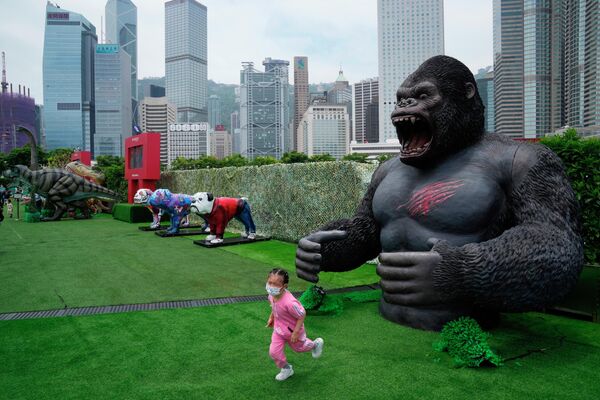 2022年5月9日，香港公園，一名女孩戴著口罩從大猩猩模型中逃離。(美聯社攝/Kin Cheung) - 俄羅斯衛星通訊社