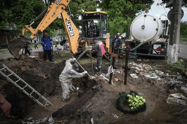 馬里烏波爾市政職工為搶修水管設施挖掘路邊墓葬。 - 俄羅斯衛星通訊社