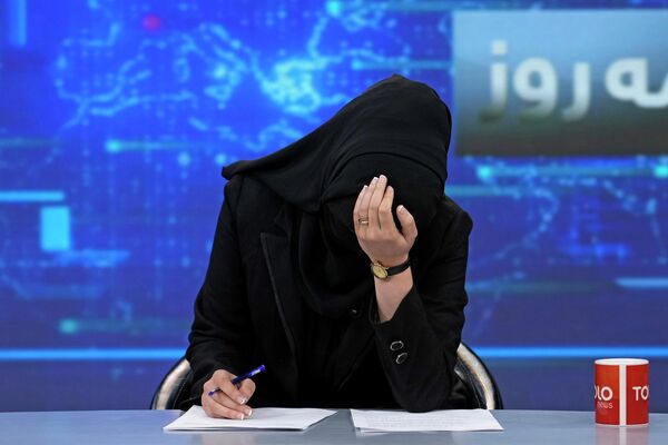 2022年5月22日，阿富汗喀布爾，一名電視女主播戴著面罩低頭閱讀新聞。該國塔利班下令，要求女主播在播報時必須遮臉。 - 俄羅斯衛星通訊社
