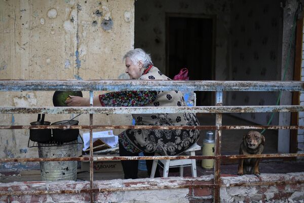 一名婦女在馬里烏波爾公寓陽台上烹制食物。 - 俄羅斯衛星通訊社