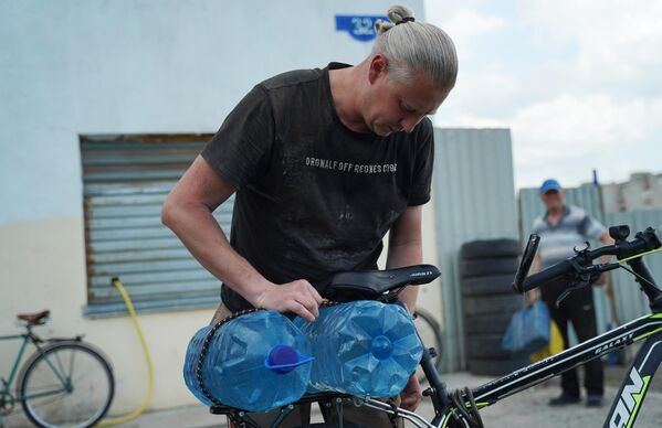 魯比日內當地居民把裝飲用水的小水桶綁到一口水井旁的自行車上。 - 俄羅斯衛星通訊社
