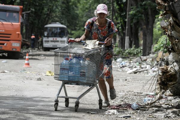 一名女子推著一輛購物車走在馬里烏波爾的街道上。 - 俄羅斯衛星通訊社