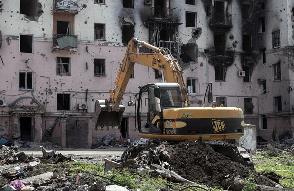 馬里烏波爾的一條街道上，一輛挖掘機正在挖掘一處平民埋葬地，以便將其重新安葬。 - 俄羅斯衛星通訊社