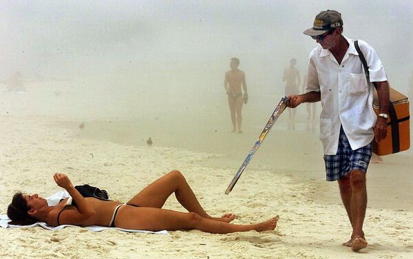 1999年12月9日，里約熱內盧的科帕卡巴納海灘上，一個賣冰激凌的小販從一個曬太陽的人身邊走過。 - 俄羅斯衛星通訊社