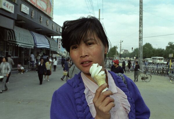 中國北京的一條街道上，一名女子正在吃著甜筒冰淇淋。 - 俄羅斯衛星通訊社