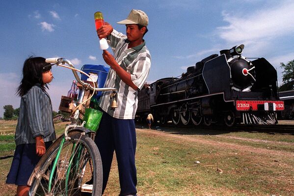 2000年2月6日，一輛老式蒸汽火車“太平洋231”在金邊以南50公里處的一個小站檢查停車時，一名柬埔寨男子正在為一個小女孩準備冰激凌。 - 俄羅斯衛星通訊社