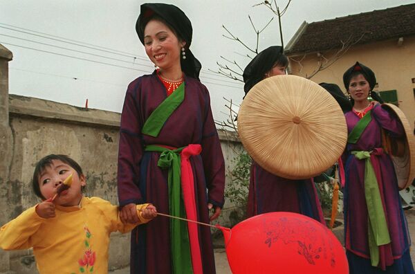 越南北宁省，一名小女孩在身着传统服装的官贺歌手旁边吃冰。在红河三角洲北部的这一地区，官贺民歌是一种非常受欢迎的传统民歌。 - 俄罗斯卫星通讯社