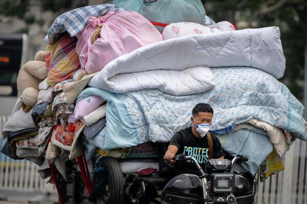 2022年6月16日，北京一名戴著口罩的男子開著一輛裝滿被褥的手推車在街道上行駛。 - 俄羅斯衛星通訊社