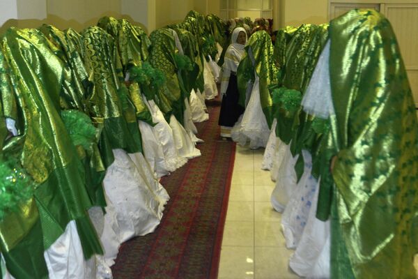 2022年6月13日，喀布尔的新娘们站在一个婚礼大厅内，等待大规模结婚仪式的开始。数十名隐藏在厚厚的绿色披肩中的阿富汗妇女在喀布尔举行的一场朴素的集体婚礼上结婚，数百名宾客和持枪的塔利班战士参加了这一典礼。 - 俄罗斯卫星通讯社