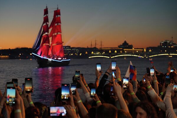 在聖彼得堡“紅帆節”期間，涅瓦河岸邊的民眾用手機拍攝巨大的“紅帆船”通過。 - 俄羅斯衛星通訊社