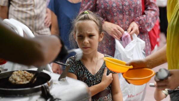 一個小姑娘在馬里烏波爾街上的野戰廚房附近排隊領取熱食。 - 俄羅斯衛星通訊社