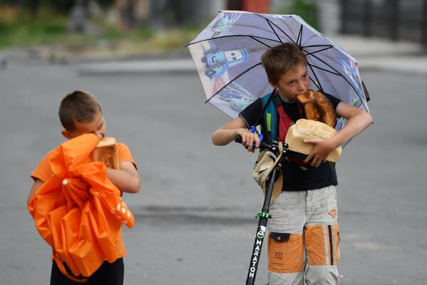 马里乌波尔一个流动援助站附近的两个男孩正在吃面包。 - 俄罗斯卫星通讯社