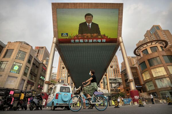 一位佩戴口罩的中国居民骑车经过正在转播习近平视察香港报道的显示屏。 - 俄罗斯卫星通讯社