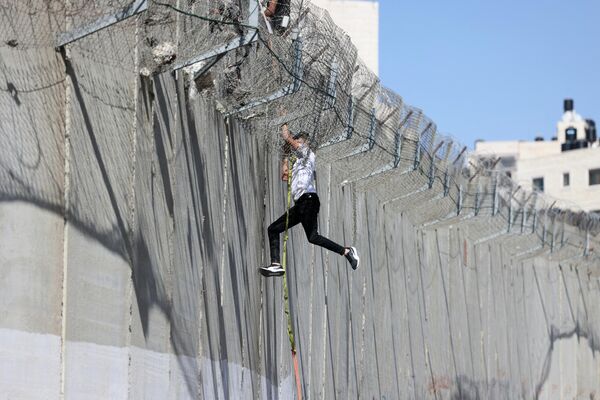 一名年輕人爬過以色列隔離牆的混凝土牆上，垂降到東耶路撒冷的拜特哈寧地區。 - 俄羅斯衛星通訊社