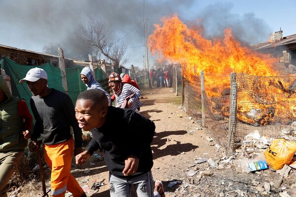 在南非舉行的抗議非法採礦的示威活動中，Mohlenken社區成員從一場燒毀非法採礦者物品的大火中逃離。 - 俄羅斯衛星通訊社