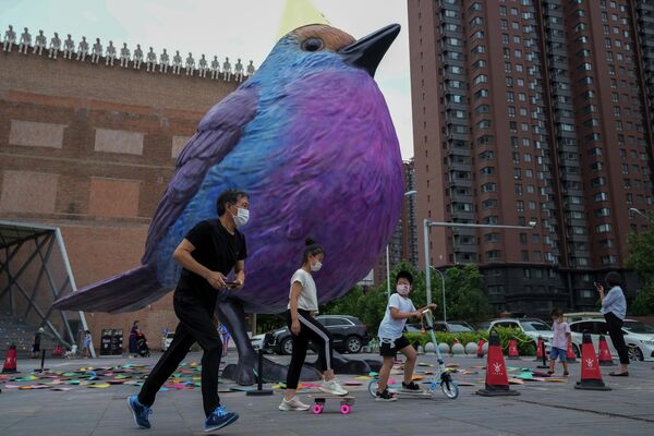 北京，戴著口罩的市民從美術館附近展出的巨鳥雕塑旁經過。 - 俄羅斯衛星通訊社