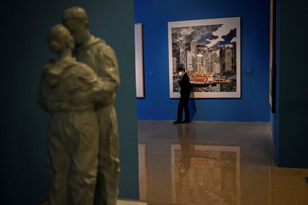 2022年7月1日，在国家博物馆举办的庆祝香港回归25周年展览期间，一名工作人员站在一幅描绘香港城市天际线的画作旁。(Photo by Jade GAO / AFP)  - 俄罗斯卫星通讯社