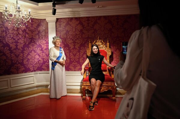 一名女子在北京杜莎夫人蜡像馆与英国女王伊丽莎白二世的蜡像合影留念。 - 俄罗斯卫星通讯社