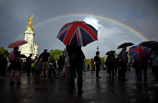 在倫敦白金漢宮對面的維多利亞女王紀念碑前，一名男子手持繪有旗幟的雨傘。 - 俄羅斯衛星通訊社