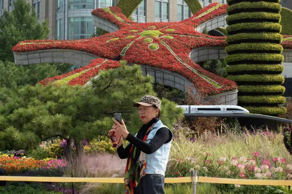 行人在北京的街心花園前拍照。 行人在北京的街心花園前拍照。 - 俄羅斯衛星通訊社