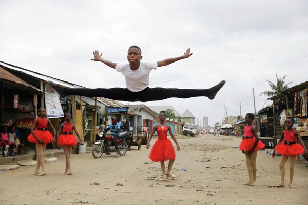 2020年8月18日，尼日利亞拉各斯，芭蕾舞學生Anthony Mmesoma Madu（中）在街上跳舞，其他舞者在一旁觀看。這名11歲兒童在雨中赤腳跳舞的視頻在社交媒體上瘋傳。Madu的舞蹈練習令人印象深刻，為他贏得了美國芭蕾舞劇院的芭蕾舞獎學金。(攝影：AP Photo/Sunday Alamba) - 俄羅斯衛星通訊社