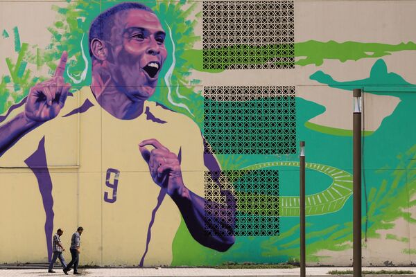 11月6日，2022年卡塔尔世界杯开幕前夕，人们从著名球星、前巴西前锋罗纳尔多的壁画前走过。 - 俄罗斯卫星通讯社
