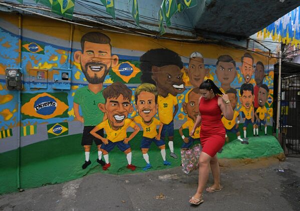11月23日，在巴西里約熱內盧的貧民窟，一名婦女從一幅描繪巴西世界杯足球隊的壁畫前走過。- - 俄羅斯衛星通訊社