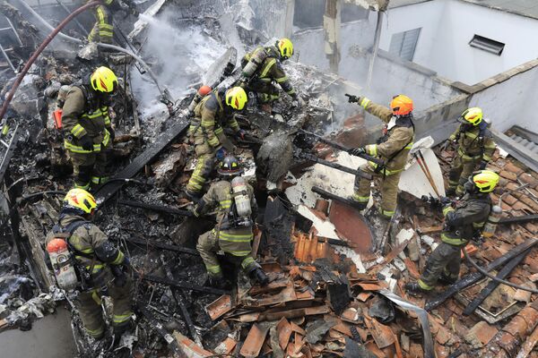 2022年11月21日，消防员在一架小型飞机的坠毁现场展开工作，该飞机坠落在哥伦比亚麦德林一个居民区的屋顶，造成至少8人死亡，包括两名机组成员和6名乘客。 - 俄罗斯卫星通讯社