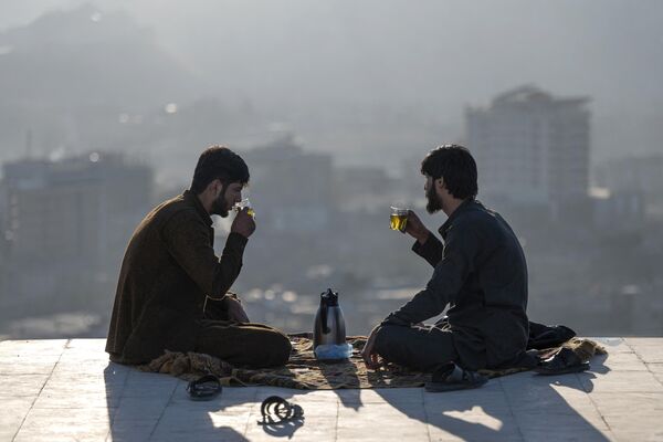 2022年11月23日，两名阿富汗男子在俯瞰喀布尔的纳迪尔汗山顶喝茶。 - 俄罗斯卫星通讯社