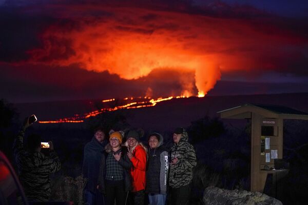 2022年11月30日，夏威夷希洛附近，人们在夏威夷冒纳罗亚火山喷发的熔岩前合影。 - 俄罗斯卫星通讯社
