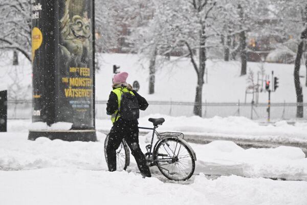 2022年11月21日，瑞典南部遭遇大雪后，一名女子在斯德哥尔摩推着她的自行车穿过雪地。 - 俄罗斯卫星通讯社
